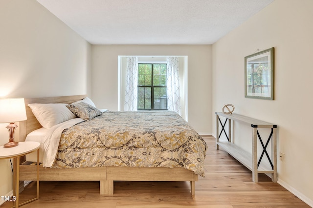 bedroom featuring light hardwood / wood-style floors and a textured ceiling