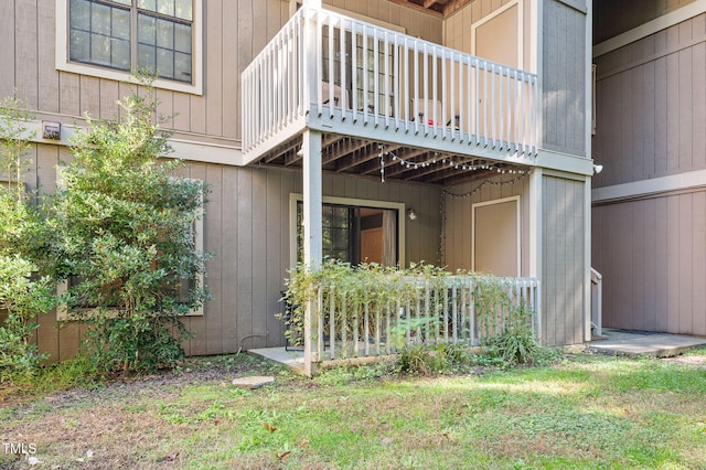 doorway to property featuring a balcony and a lawn