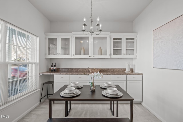 bar featuring white cabinets, light stone countertops, light carpet, and hanging light fixtures