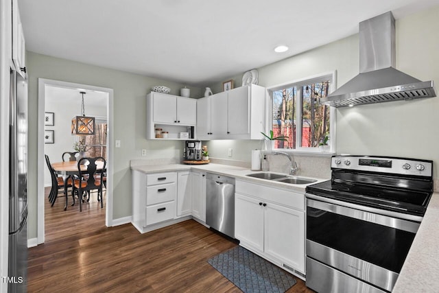 kitchen featuring white cabinets, appliances with stainless steel finishes, wall chimney range hood, and sink