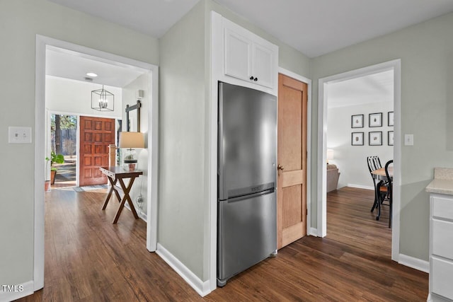 kitchen with stainless steel refrigerator, a notable chandelier, dark hardwood / wood-style flooring, and white cabinetry