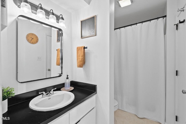 bathroom with toilet, vanity, and tile patterned floors