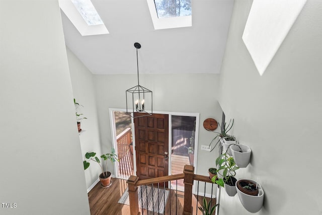 foyer entrance featuring lofted ceiling with skylight, a chandelier, and dark hardwood / wood-style floors