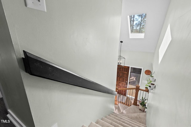 staircase with a skylight and high vaulted ceiling