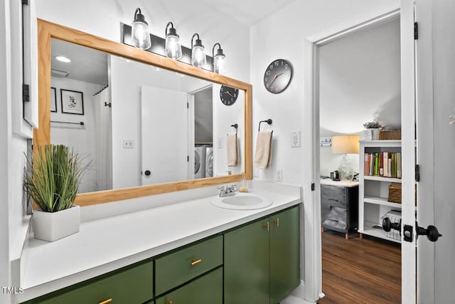 bathroom featuring washing machine and dryer, vanity, and hardwood / wood-style floors