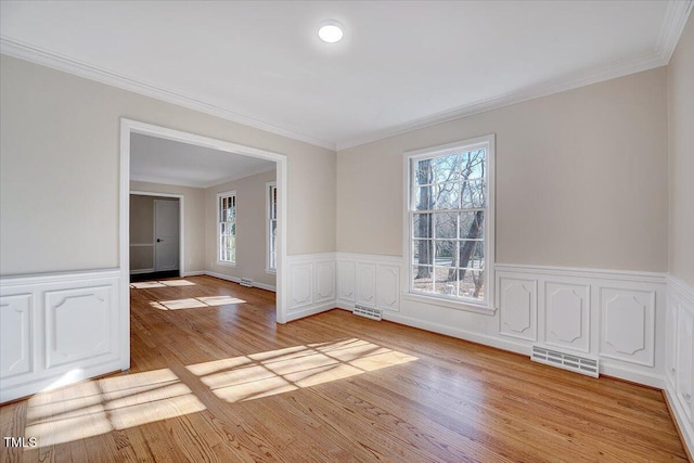 empty room featuring light wood-type flooring and ornamental molding