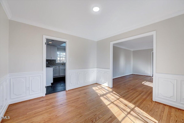 unfurnished room featuring light wood-type flooring and ornamental molding