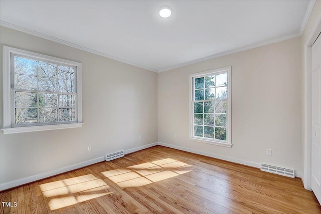 empty room with plenty of natural light, ornamental molding, and light hardwood / wood-style flooring