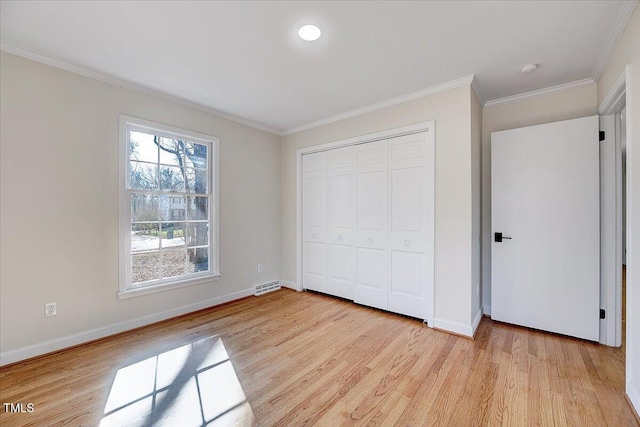 unfurnished bedroom with crown molding, a closet, and light wood-type flooring