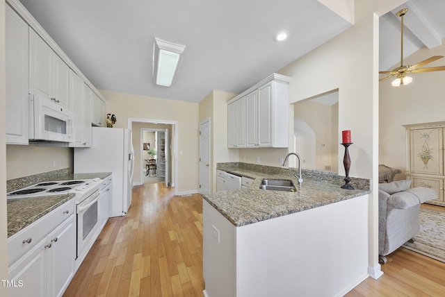 kitchen with light hardwood / wood-style floors, kitchen peninsula, white appliances, dark stone countertops, and white cabinets