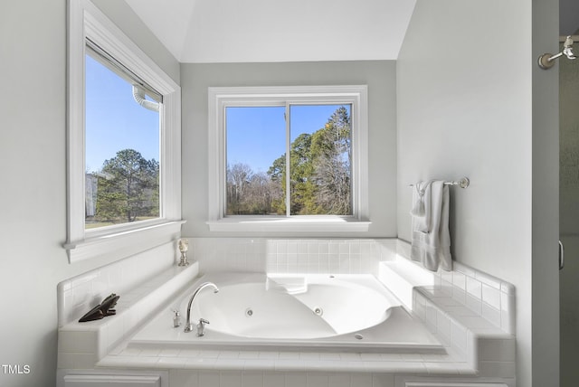 bathroom with tiled bath, lofted ceiling, and plenty of natural light