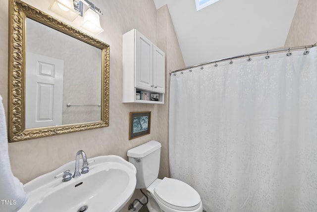 bathroom with sink, toilet, and vaulted ceiling