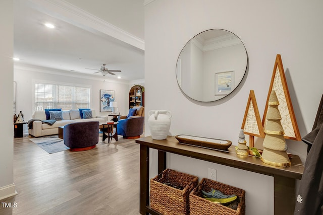 interior space with ceiling fan, wood-type flooring, and ornamental molding