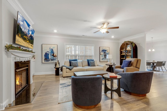 living room with ceiling fan with notable chandelier, light hardwood / wood-style flooring, and crown molding