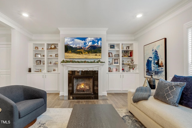 living room featuring built in shelves, crown molding, and light wood-type flooring