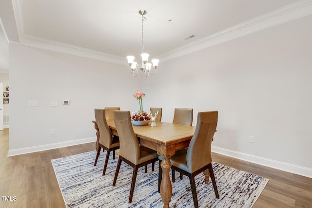 dining space featuring hardwood / wood-style flooring, crown molding, and a chandelier