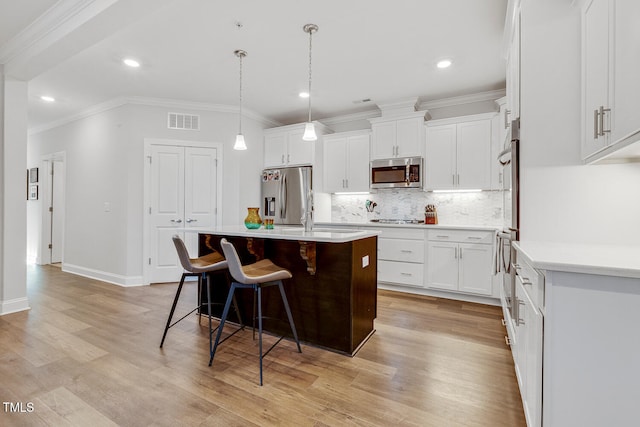 kitchen featuring a kitchen breakfast bar, a kitchen island with sink, white cabinets, and stainless steel appliances