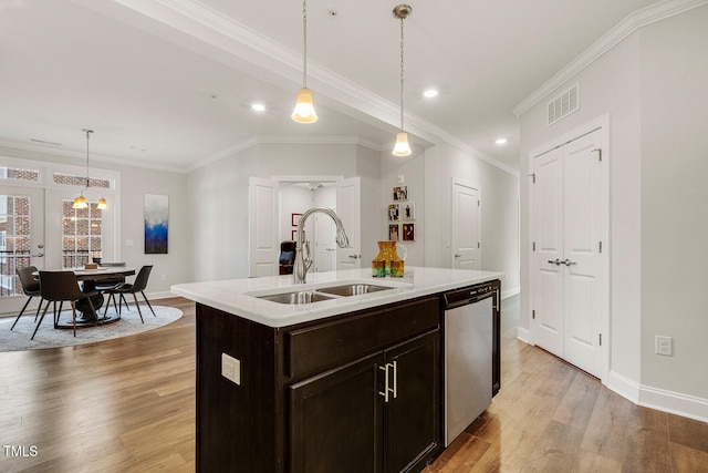 kitchen featuring stainless steel dishwasher, a kitchen island with sink, crown molding, sink, and decorative light fixtures