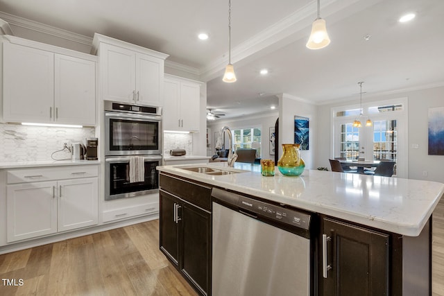 kitchen featuring white cabinets, stainless steel appliances, a kitchen island with sink, and hanging light fixtures