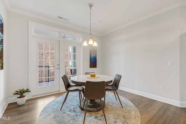 dining space featuring a chandelier, french doors, dark wood-type flooring, and ornamental molding