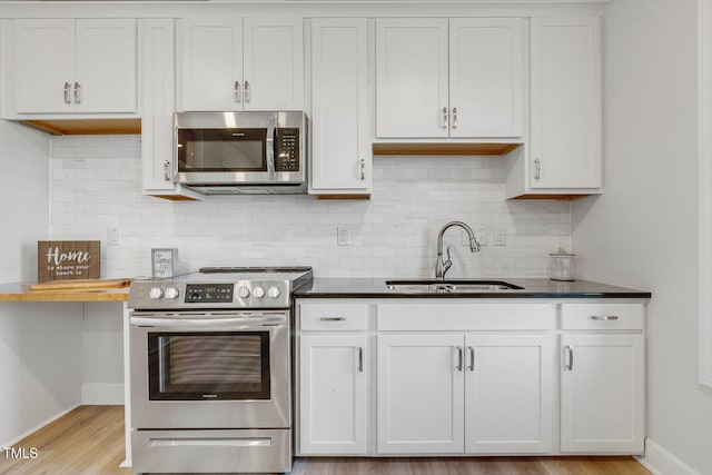 kitchen with tasteful backsplash, white cabinetry, sink, and stainless steel appliances