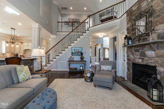 living room with a high ceiling, crown molding, dark hardwood / wood-style floors, and a stone fireplace