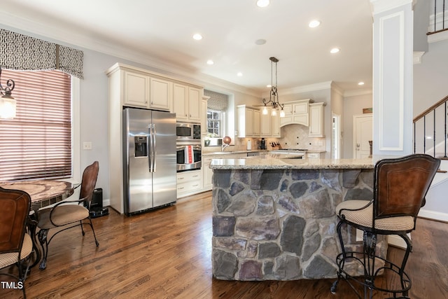 kitchen with backsplash, dark hardwood / wood-style floors, hanging light fixtures, stainless steel appliances, and light stone counters