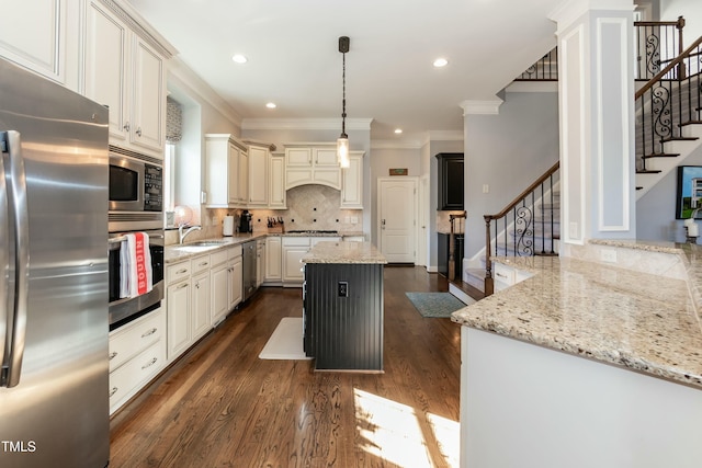 kitchen with appliances with stainless steel finishes, light stone counters, and a center island