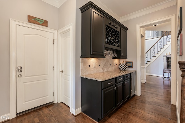 kitchen featuring tasteful backsplash, light stone countertops, dark wood-type flooring, and crown molding