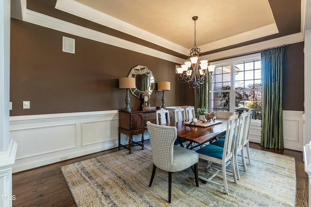 dining room featuring crown molding, dark hardwood / wood-style flooring, a raised ceiling, and a chandelier