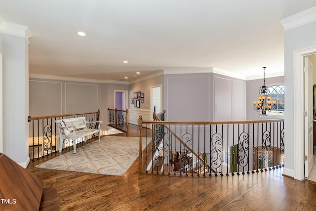 hall with ornamental molding, hardwood / wood-style floors, and a notable chandelier