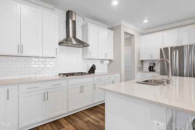 kitchen featuring decorative backsplash, stainless steel appliances, sink, wall chimney range hood, and white cabinetry