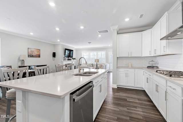 kitchen with stainless steel appliances, a kitchen island with sink, wall chimney range hood, sink, and white cabinetry