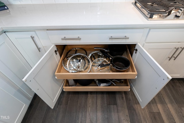 details with white cabinets, stainless steel gas stovetop, and dark wood-type flooring