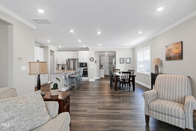 living room with sink, crown molding, and dark wood-type flooring