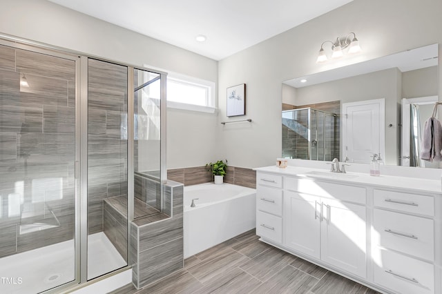 bathroom with vanity and shower with separate bathtub