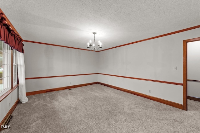 empty room featuring a textured ceiling, crown molding, light carpet, and an inviting chandelier