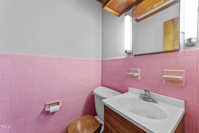 bathroom with vanity, toilet, and tile walls