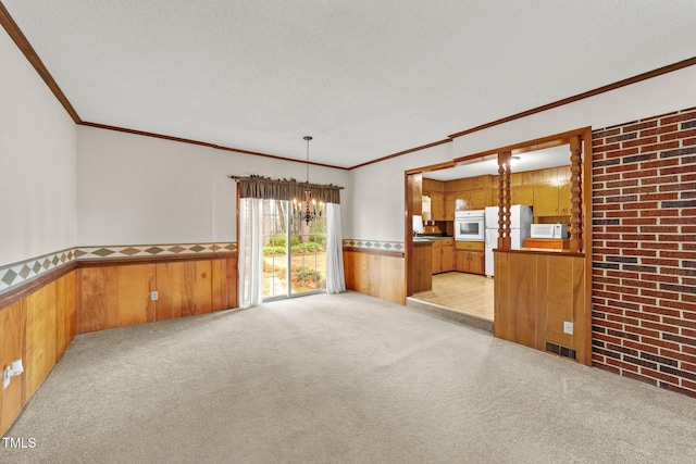 carpeted empty room with a textured ceiling, a notable chandelier, and wood walls