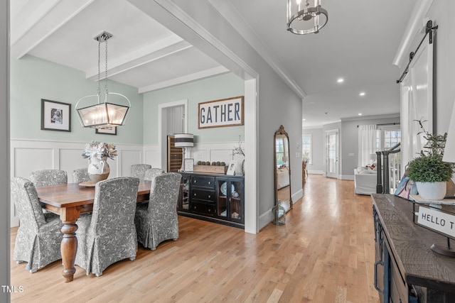 dining area featuring an inviting chandelier, light wood-type flooring, crown molding, and a barn door