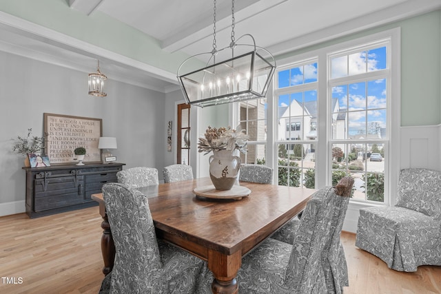 dining area with beam ceiling, light hardwood / wood-style floors, and a chandelier