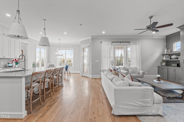 living room with ceiling fan, light hardwood / wood-style flooring, ornamental molding, and sink