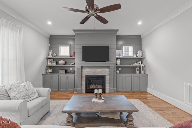 living room featuring a fireplace, ceiling fan, light hardwood / wood-style floors, and ornamental molding