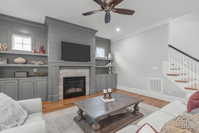 living room featuring ceiling fan, a fireplace, light wood-type flooring, and a healthy amount of sunlight