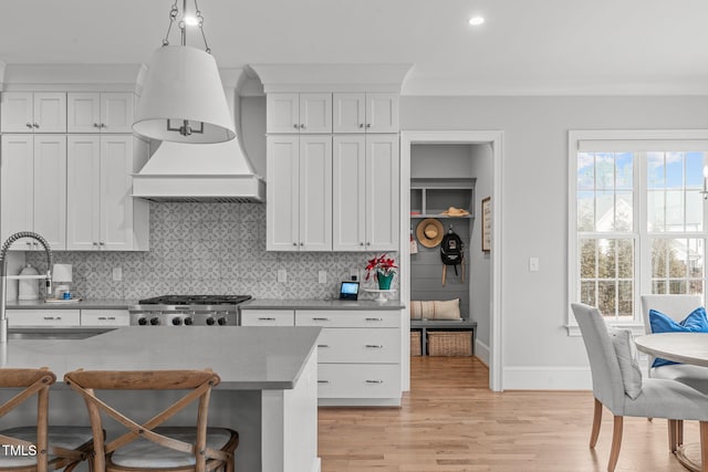 kitchen with light wood-type flooring, sink, white cabinetry, decorative light fixtures, and tasteful backsplash