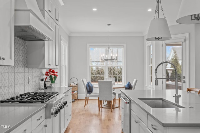 kitchen featuring white cabinets, hanging light fixtures, sink, and custom range hood