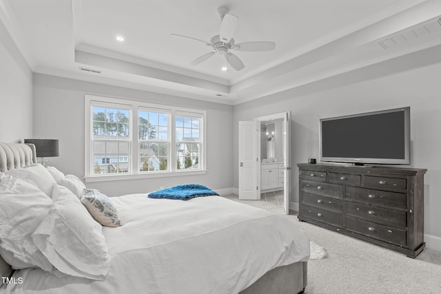 bedroom with a raised ceiling, light colored carpet, crown molding, ceiling fan, and ensuite bathroom