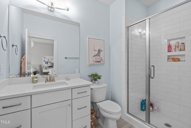 bathroom with toilet, vanity, and a shower with shower door