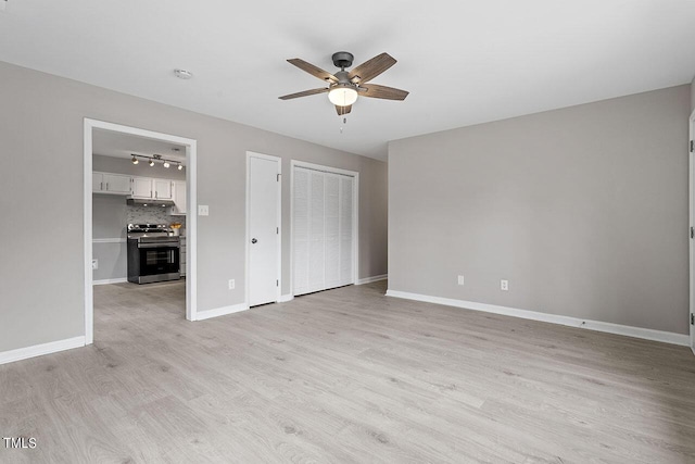 unfurnished bedroom featuring ceiling fan, two closets, rail lighting, and light hardwood / wood-style flooring