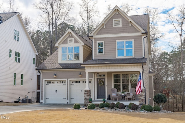 craftsman inspired home with a garage, covered porch, and central air condition unit